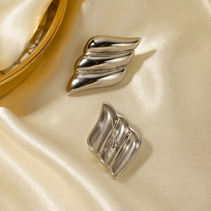 Silver wavy stainless steel stud earrings on luxury cream silk background