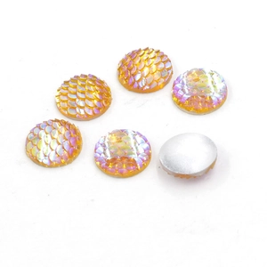 Macro detail of 14mm round mermaid scale resin cabochons with iridescent orange glow
