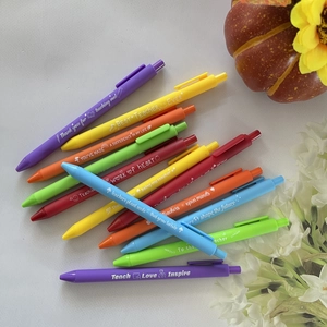 Flat lay of colorful retractable gel pens with teacher appreciation quotes on desk