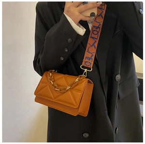 Detail of caramel quilted crossbody bag featuring amber chain and colorful wide strap