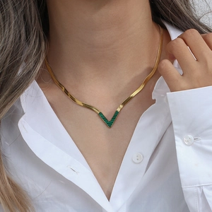Detail of 18K gold-plated snake chain necklace with V-shaped malachite pendant on model