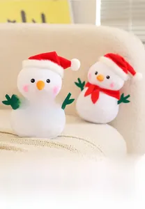 Detail of plush Christmas snowman dolls with red hats and checkered scarves on a sofa