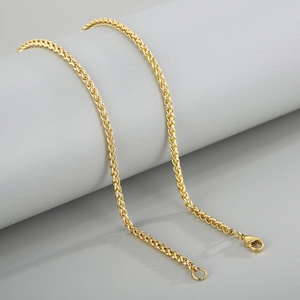 Golden 3mm stainless steel wheat chain necklace displayed on a minimal gray cylinder