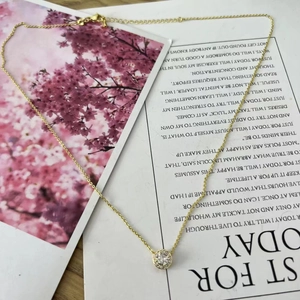 Detail of a gold necklace featuring a round halo pendant with sparkling cubic zirconia