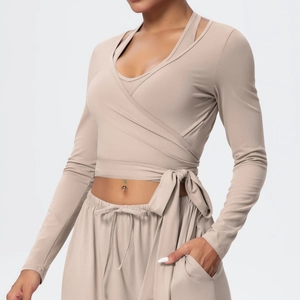 Detail view of beige wrap-style yoga top with waist tie and elastic drawstring pants