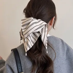 Élastique à cheveux chic à rayures blanc cassé avec perles porté par un mannequin