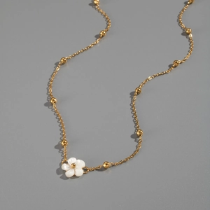 Detailed macro view of white shell flower pendant on 18K gold plated beaded chain
