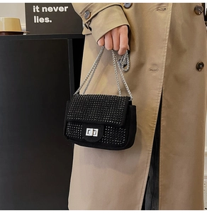 Detail of black rhinestone evening bag with silver twist lock and chain on khaki coat