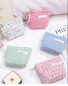 Detailed view of tweed coin purses in various colors with pearl zipper charms