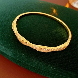 Detail of gold-plated bangle with pavé-set cubic zirconia on green velvet box