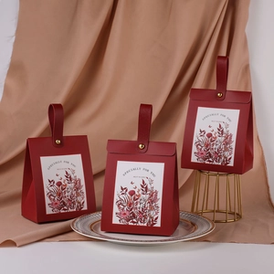 Detail of red wedding favor box with floral sticker and gold fastener on display