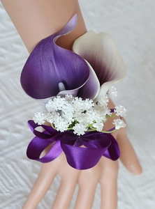 Detail of purple and white calla lily wrist corsage with a large satin ribbon bow