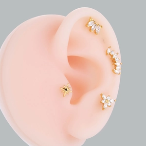 Detail of four-piece gold cartilage earring set with zircon stars and floral studs