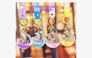 Close-up of moon-shaped liquid quicksand keychains with bunnies and stars in four colors