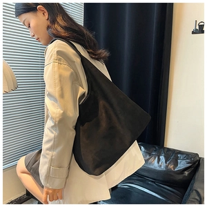 Detail of a large black suede tote bag shown on model for a casual commute look