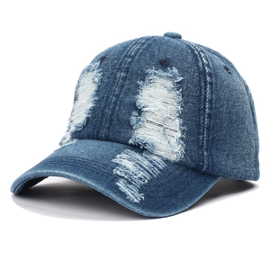 Distressed dark blue denim baseball cap with vintage frayed holes and retro street style design