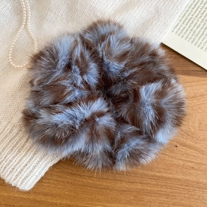 Primo piano di elastico per capelli in peluche a righe marroni e blu su legno