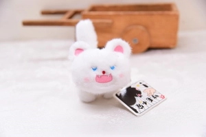 Close-up of fluffy white cat plush keychain with blue eyes and pink embroidery details