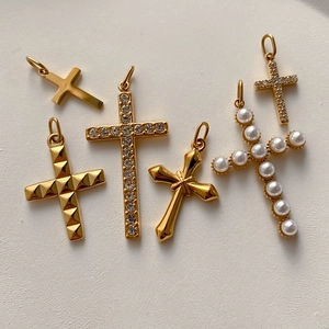 Collezione di ciondoli a croce dorati con perle, zirconi e motivi metallici testurizzati