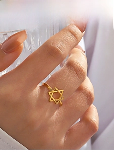 Detail of a hollow gold hexagram star ring worn on finger with soft lighting