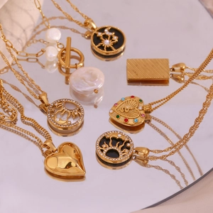 Detail of vintage 18K gold plated pendants with sun, moon, heart and pearl accents