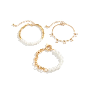 Detailed view of three-piece gold-tone bracelet set with faux pearls and OT buckle