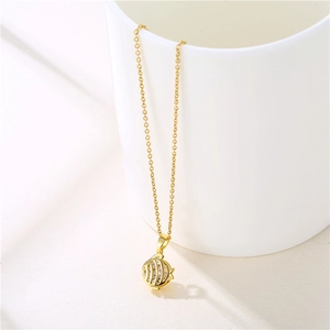 Golden fish pendant necklace in stainless steel with clear zircon hanging on a white cup