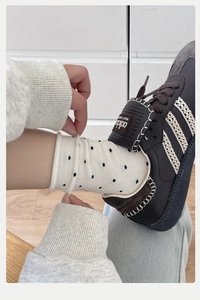 Detailed view of white cotton socks with black polka dots and ribbed elastic cuffs