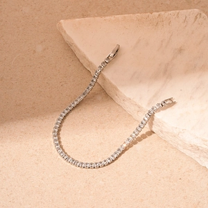 Détail macro d'un bracelet tennis argenté avec cristaux carrés sur supports en pierre