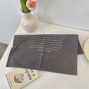 Modern dark grey fabric placemat with white Scandinavian design typography on a table