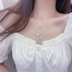 Detail of heart shell pendant necklace on neck showing elegant gold tassel chain