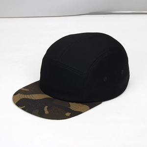 Close-up of a 5-panel camper cap with black crown and camouflage flat brim detail