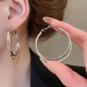Boucles d'oreilles créoles doubles géométriques argentées montrées sur un mannequin