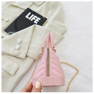 Detailed view of pink jelly shell bag with gold chain strap on soft velvet fabric
