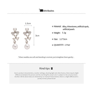 Détail de boucles d'oreilles fleur avec pétales oeil-de-chat, strass et perles