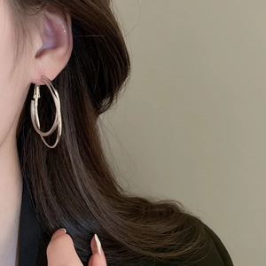 Close-up of dual-layer golden hoop earrings with textured mesh and smooth metal design