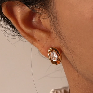 Macro view of gold stainless steel oval earring with clear zircon stone on ear