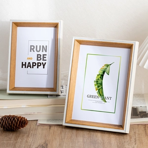 Minimalist wooden photo frame set with leaf prints on books in a cozy setting