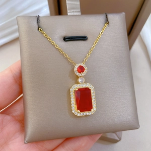 Macro shot of gold necklace with red rectangular gemstone and micro-inlaid diamonds