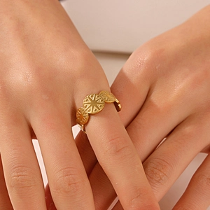 Golden stainless steel starburst ring with circular openwork design worn on a finger