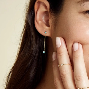 Detail of elegant gold tassel earrings with turquoise stones and adjustable crystal ring