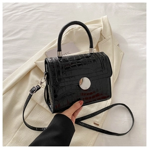 Detail of black crocodile texture handbag with glossy finish and silver metal lock