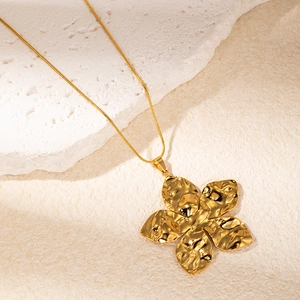 Textured gold flower pendant necklace with elegant snake chain on a stone background