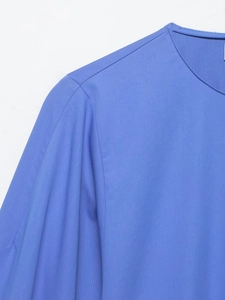 Détail du col rond et des coutures d'épaule sur la chemise en popeline bleue à manches bouffantes
