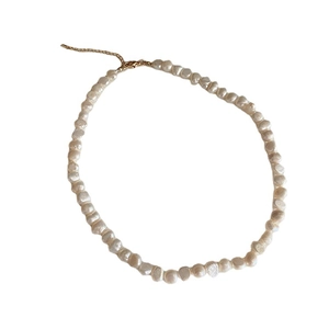 Collana di perle d'acqua dolce barocche con chiusura dorata regolabile su sfondo bianco