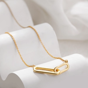 Detail shot of 18K gold double interlocking rectangular pendants on a fine chain necklace