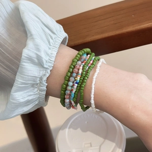 Close-up of bohemian multilayer beaded bracelets with green and white resin beads