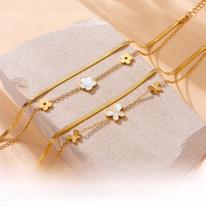 Detail of gold butterfly and flower pendants on a snake and ring layered anklet chain