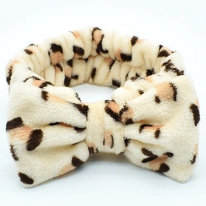 Plush coral fleece leopard print headband with a large bow for face washing and makeup