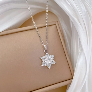 Macro shot of silver snowflake pendant with micro-pave cubic zirconia on white silk